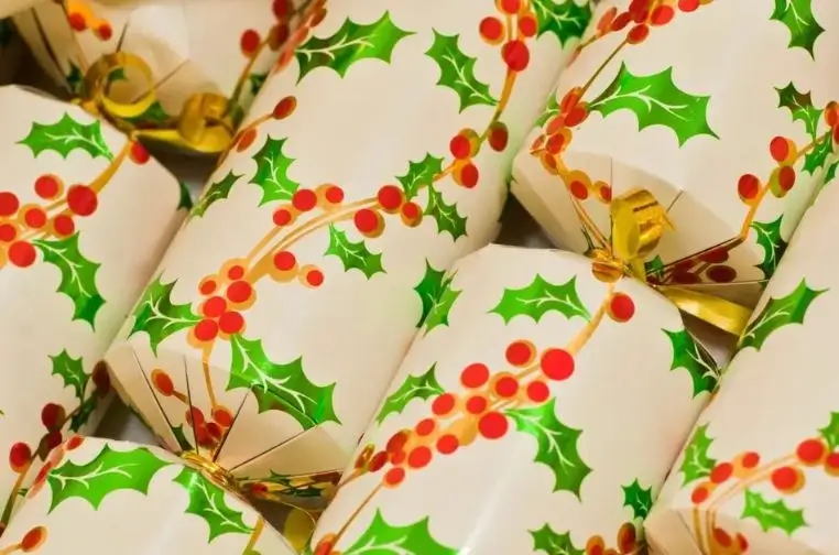 DIY Christmas crackers in progress, with colorful paper, ribbons, and small gifts on a craft table, showing how to make them at home for the 2025 holiday season